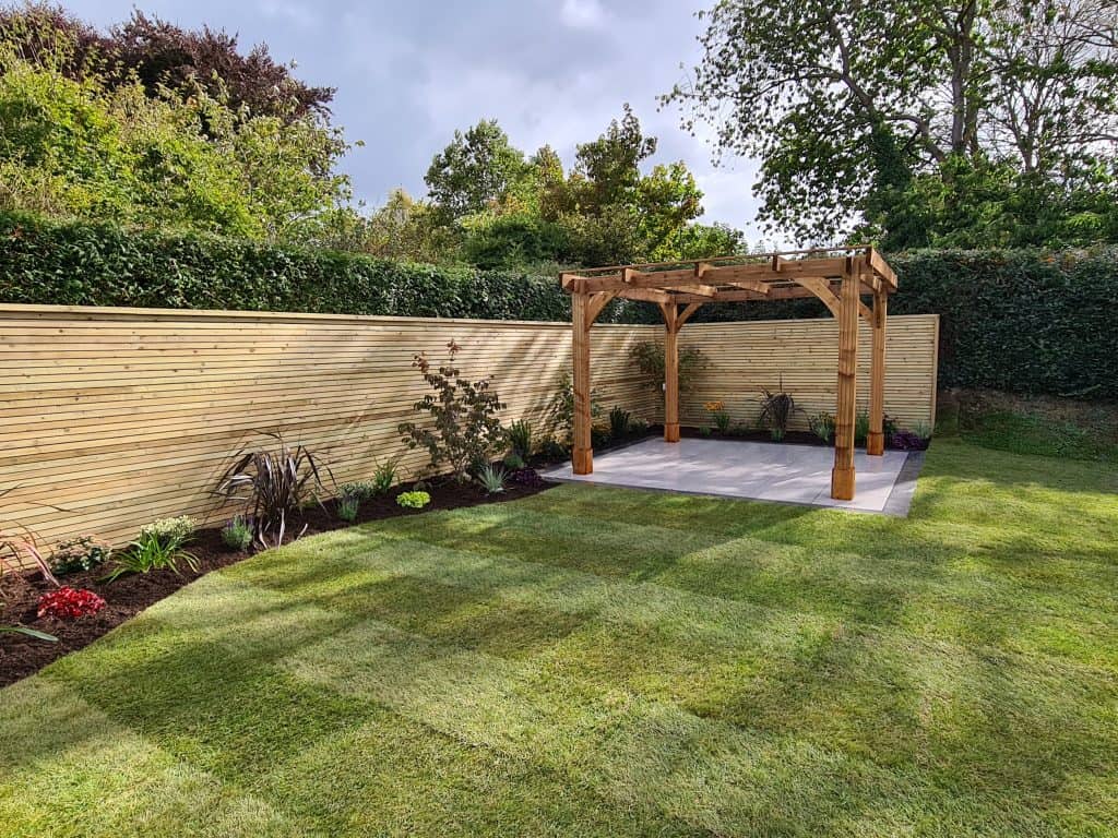 Garden landscaping with a wooden pergola in North Devon by Evergreen Landscaping.